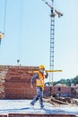 Bearded worker in reflective vest and hardhat walking with spirit level across Royalty Free Stock Photo