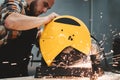 Bearded worker using electrical grinding machine in service station. Work in action. Sparks fly apart