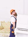 Bearded workman lifting piano with great force. Builder removing stuff before home renovation isolated on white