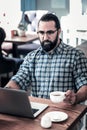 Bearded writer feeling serious while checking his article for magazine