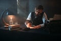 Bearded writer in glasses writes with a feather Royalty Free Stock Photo