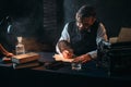 Bearded writer in glasses writes with a feather Royalty Free Stock Photo