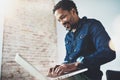 Bearded young African man smiling and using laptop while sitting at his modern coworking place.Concept of happy business Royalty Free Stock Photo