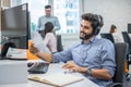 Bearded young businessman sitting in front of computer and working with paper documents in the office Royalty Free Stock Photo