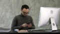 Bearded young businessman working at modern office. Man looking in his smartphone and typing something. Royalty Free Stock Photo