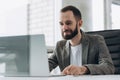 Bearded young businessman working at modern office.Man wearing white shirt and making notes on the documents.Panoramic windows