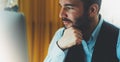 Bearded young businessman working on modern office at night. Consultant man thinking looking in monitor computer. Manager typing o Royalty Free Stock Photo