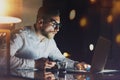 Bearded young businessman working at night office.Man using contemporary mobile notebook.Horizontal.Blurred background