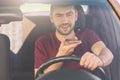 Bearded young male with thick stubble makes voice call via cell phone, drives car on high speed, risks as has distracted attention Royalty Free Stock Photo