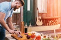 Bearded young man cutting onion for barbecue