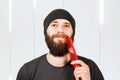 Bearded young man with hairbrush in hat combing his beard Royalty Free Stock Photo