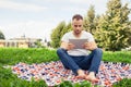 Bearded young man lying in park on blanket. He is using white ta Royalty Free Stock Photo