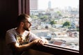 Bearded young man with sunglasses looking out of Golden Mount Wat Saket temple window over Bangkok, Thailand Royalty Free Stock Photo