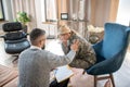 Bearded young psychologist touching shoulder of servicewoman