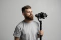 Bearder proffesional cinematographer with 3-axis gimbal and video camera on white background. Filmmaking, videography