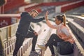 Beardy guy and beautiful female giving high-five to each other at the stadium, smiling