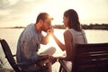 Beardy man holding and kissing hand of a woman beside river at sunset