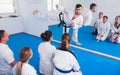 Beardy smiling instructor is showing new martial moves to adults