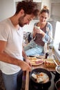 Beardy young man with curly hair making breakfast, while his female partner looking with love at him