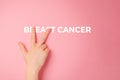 Beat cancer. A female's hand covers two letters in the word breast cancer. Close up. Pink background. Breast Cancer
