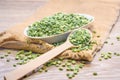 Beat green peas dry in a bowl with a wooden spoon on a wooden background.