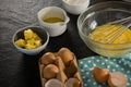 Beaten eggs, egg tray, butter, oil and flour kept on a black surface Royalty Free Stock Photo