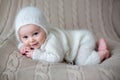 Beatiful baby boy in white knitted cloths and hat, looking curio