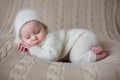 Beatiful baby boy in white knitted cloths and hat, sleeping