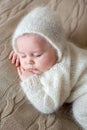 Beatiful baby boy in white knitted cloths and hat, sleeping