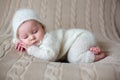 Beatiful baby boy in white knitted cloths and hat, sleeping