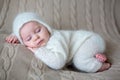 Beatiful baby boy in white knitted cloths and hat, sleeping