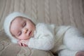 Beatiful baby boy in white knitted cloths and hat, sleeping