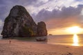 Beatiful and colorful sunset at the beach with rocks, people and a boat in Thailand