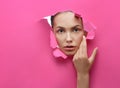 Beatiful girl looking through lacerated hole in stiff pink cardboard.