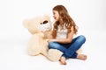 Beatiful girl sitting on floor with toy bear, telling story.