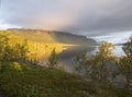 Beatiful golden light sunrise at river Lulealven in Saltoluokta in Sweden Lapland. Green rocky mountain, birch trees and clouds