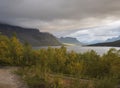 Beatiful golden light sunrise at river Lulealven in Saltoluokta in Sweden Lapland. Green rocky mountain, birch trees and clouds