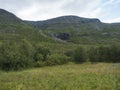 Beatiful northern landscape, tundra in Swedish Lapland with small waterfall, green hills and mountains at