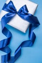 Beatiful silver gift box with blue atlas bow on a pastel blue background. Image for your design