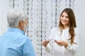 Beatiful smiling assistant showing eyeglasses to old man. Royalty Free Stock Photo