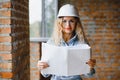 beatiful woman engineer is reviewing the plans of a construction work