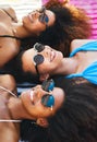 Beating the heat with the besties. a group of happy young women wearing sunglasses and relaxing at the beach.