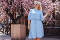Beautiful model in blue dress by spring blooming tree