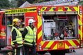 Beaulieu, Hampshire, UK - May 29 2017: Two British firemen or firefighters standing at the rear of a modern fire engine or tender