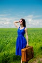 Redhead girl with suitcase standing at wheat field Royalty Free Stock Photo