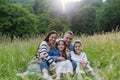 Beautfiul young family sitting in grass at meadow, enjoying together time.