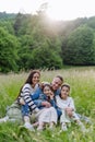 Beautfiul young family sitting in grass at meadow, enjoying together time.