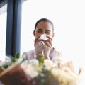 These are beauti...achoo. a young businesswoman blowing her nose in front of a bouquet of flowers.