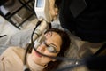 Beautician using laser handle on middle aged woman face while making laser skin resurfacing in aesthetic medicine