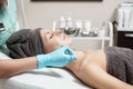 Beautician applies face mask with brush to beautiful young woman in Spa salon. cosmetic procedure skin care. Royalty Free Stock Photo